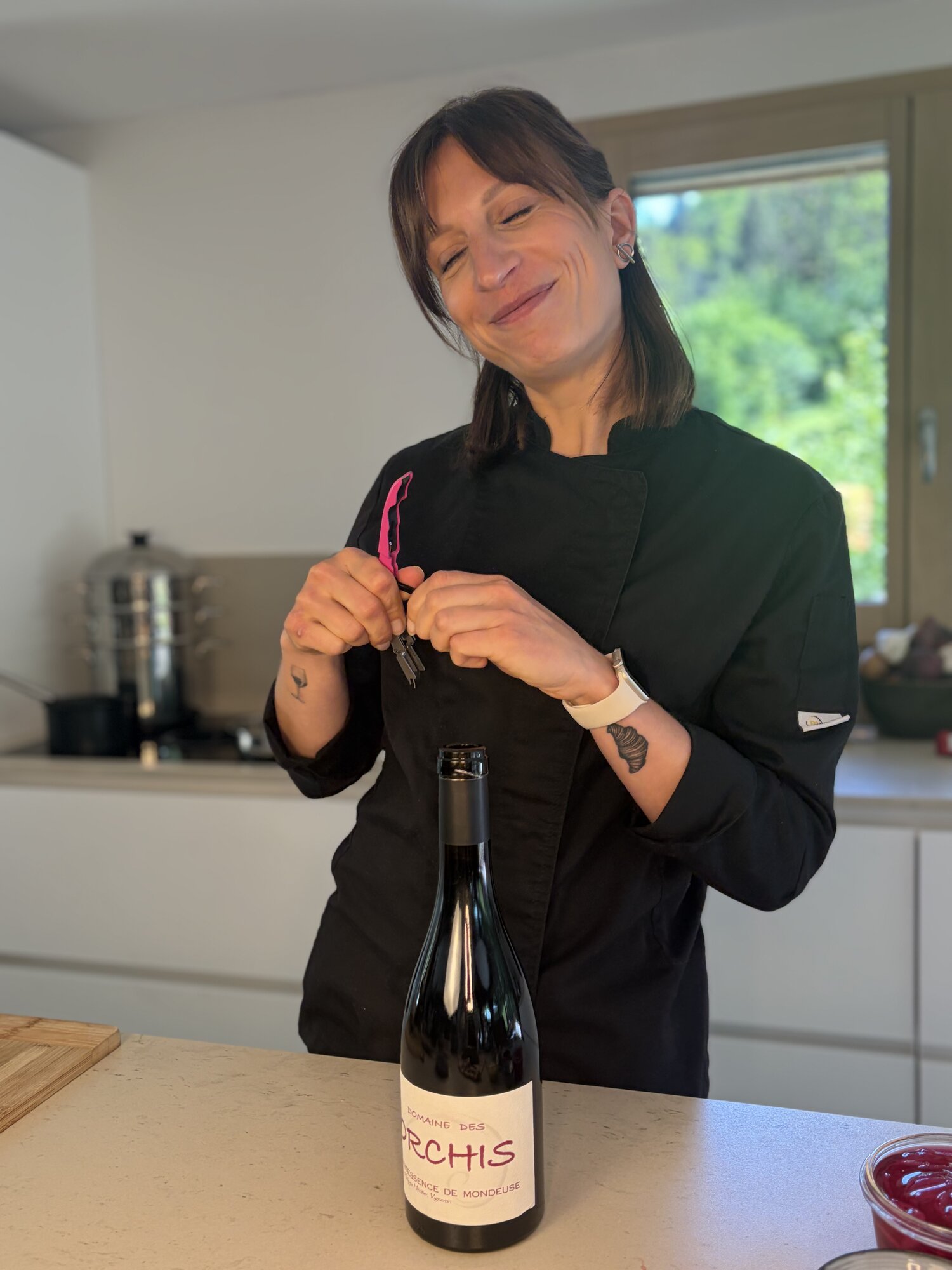 Justine ouvrant une bouteille de Mondeuse, sourire complice