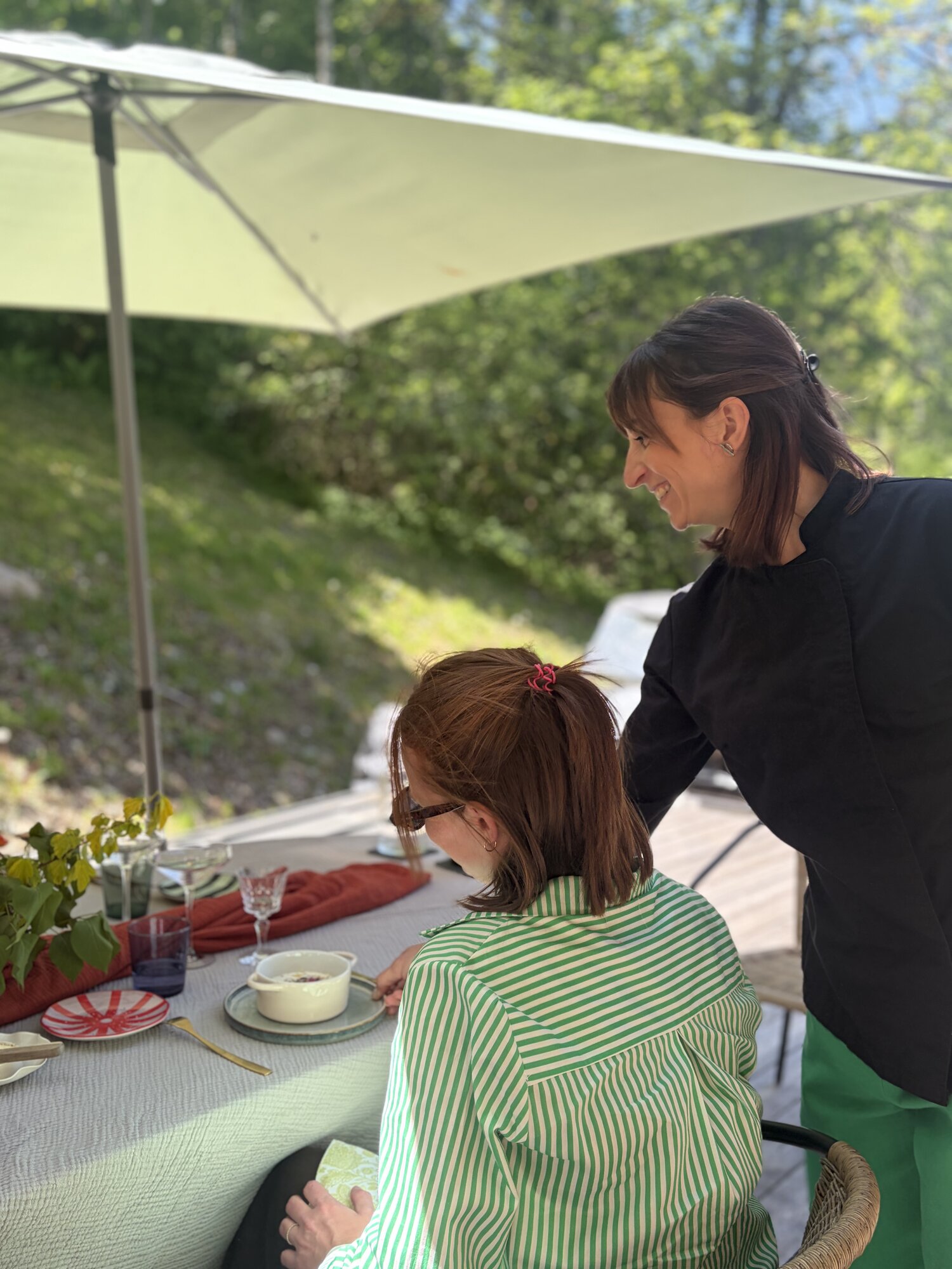 Cheffe au service, table dressée à l'extérieur sous une voile d'ombrage